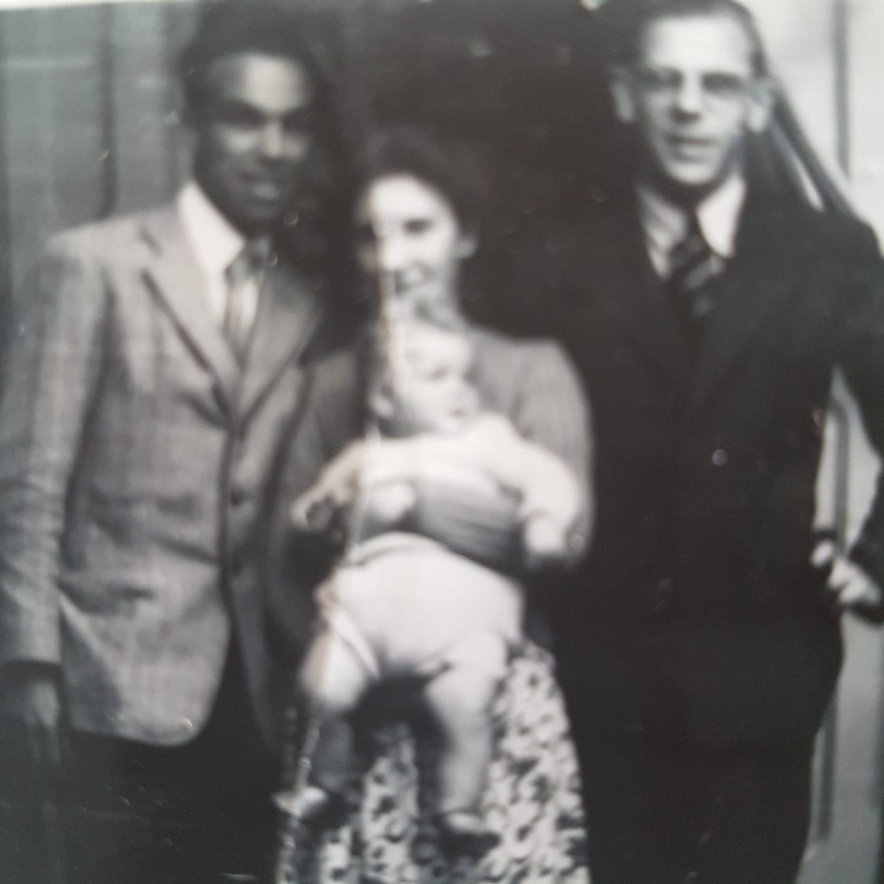 Charlie Hutchison poses with his wife Patricia, holding their first child, John. Unidentified man on the right. Late 1940s.